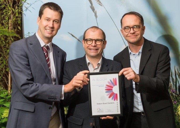 stuart sexton, greg burt and a judge hold the silver cetificate and smile for the camera